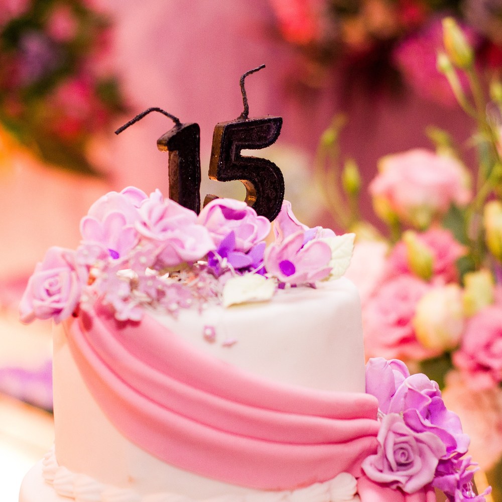 A pink and white celebration cake with sugar flowers and number candles