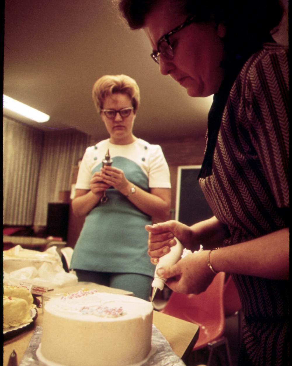 Hands piping icing onto a cake by hand